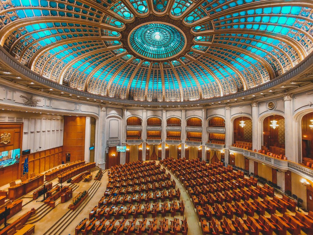 Vibrant interior of a parliament hall with a grand dome and intricate architecture.