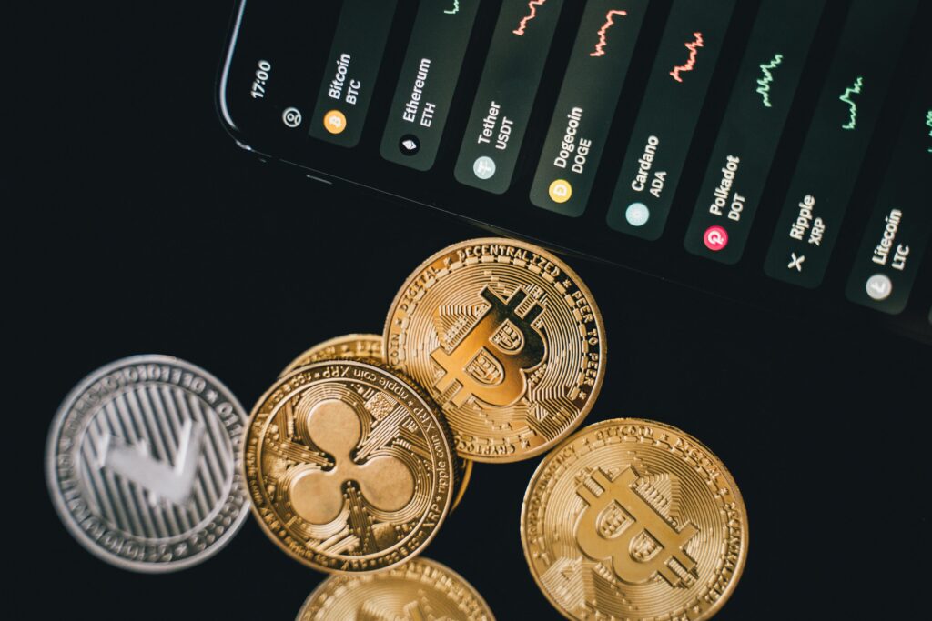 Close-up view of various cryptocurrency coins with a digital market display in the background.